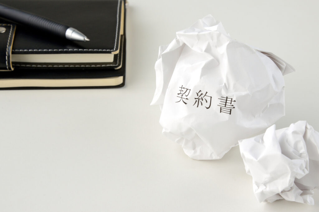 丸まった紙の契約書と手帳とボールペン